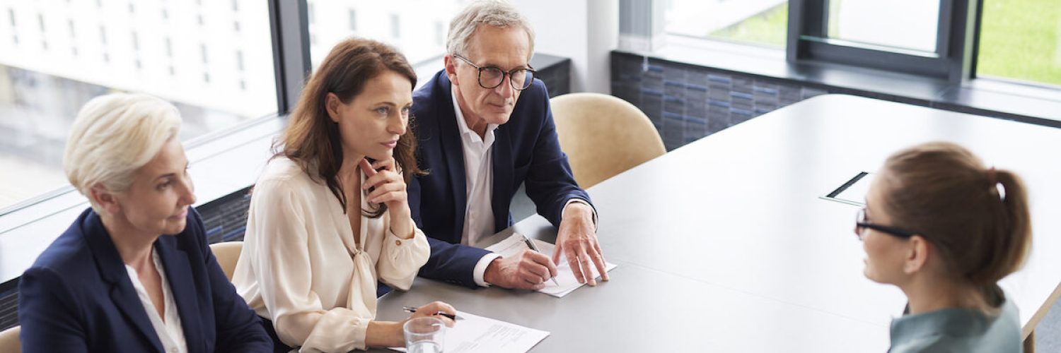 Woman during job interview and three elegant members of management