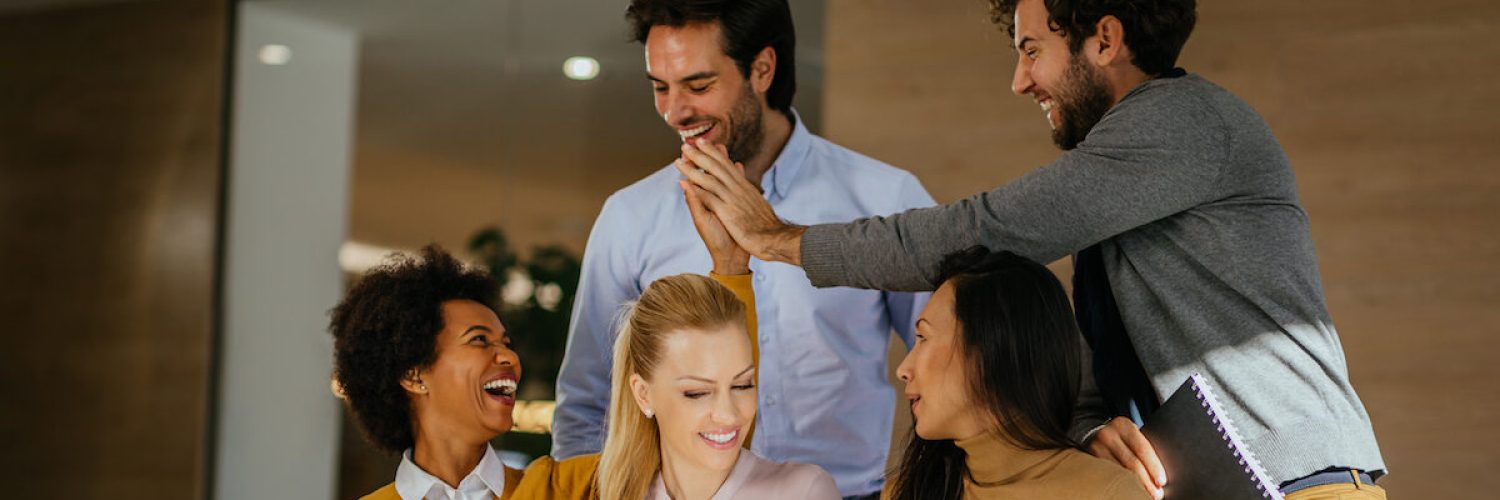 Young coworkers having a discussion and using technology in front of office during coffee break