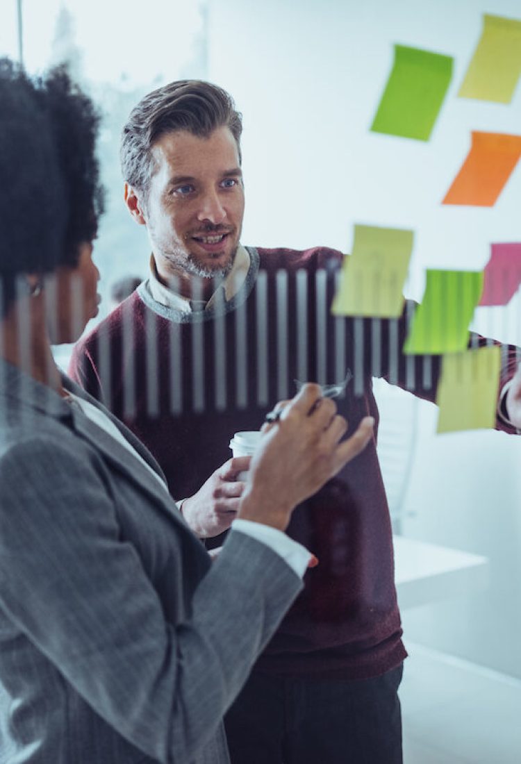 Businesspeople brainstorming with notes on a glass wall