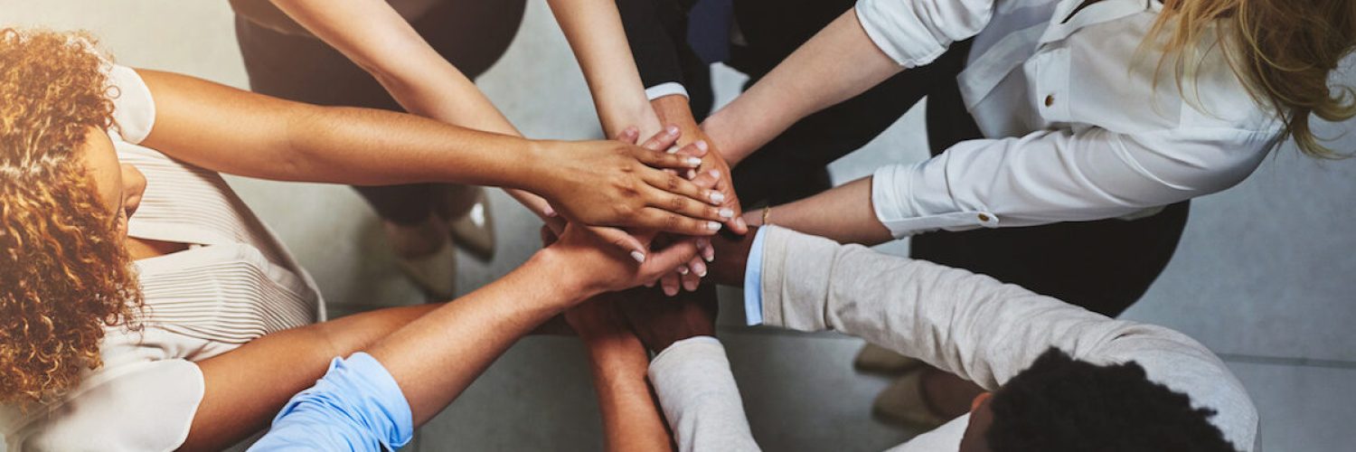 High angle shot of a group of colleagues joining their hands in solidarity.