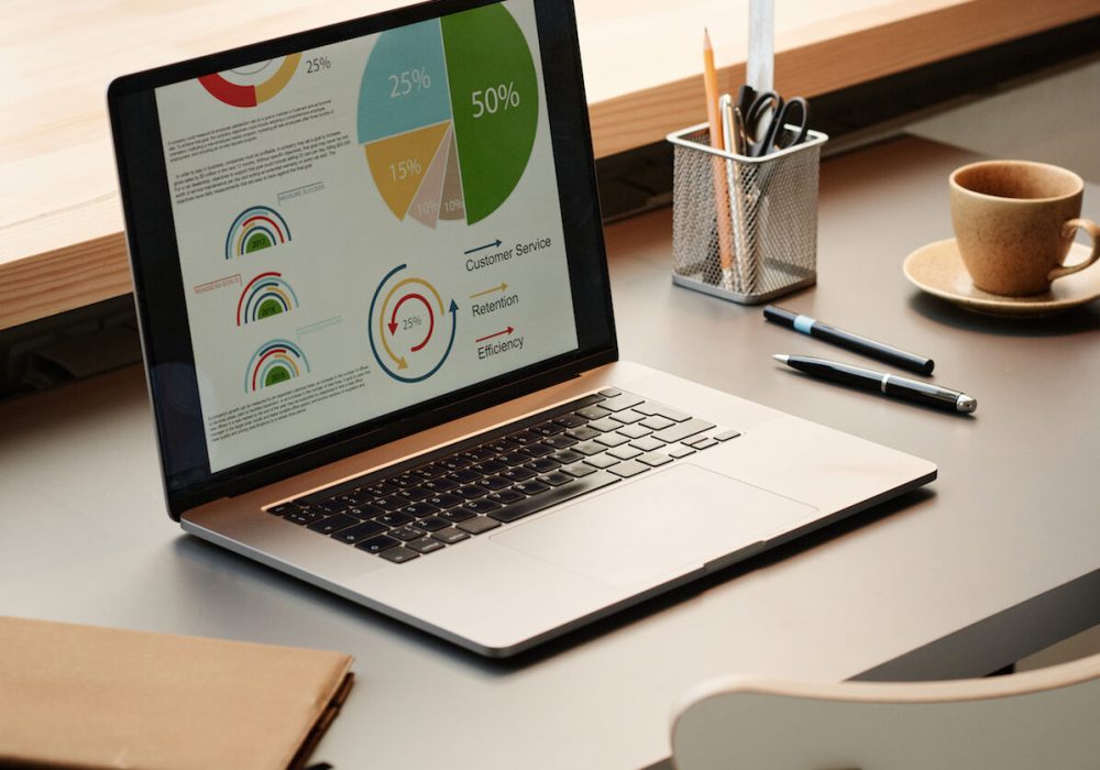 Close-up of laptop with colorful financial graphs on the screen on the table at office