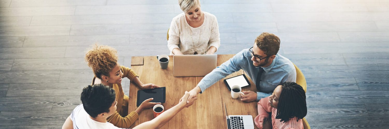 High angle shot of businesspeople shaking hands during a meeting in an office.