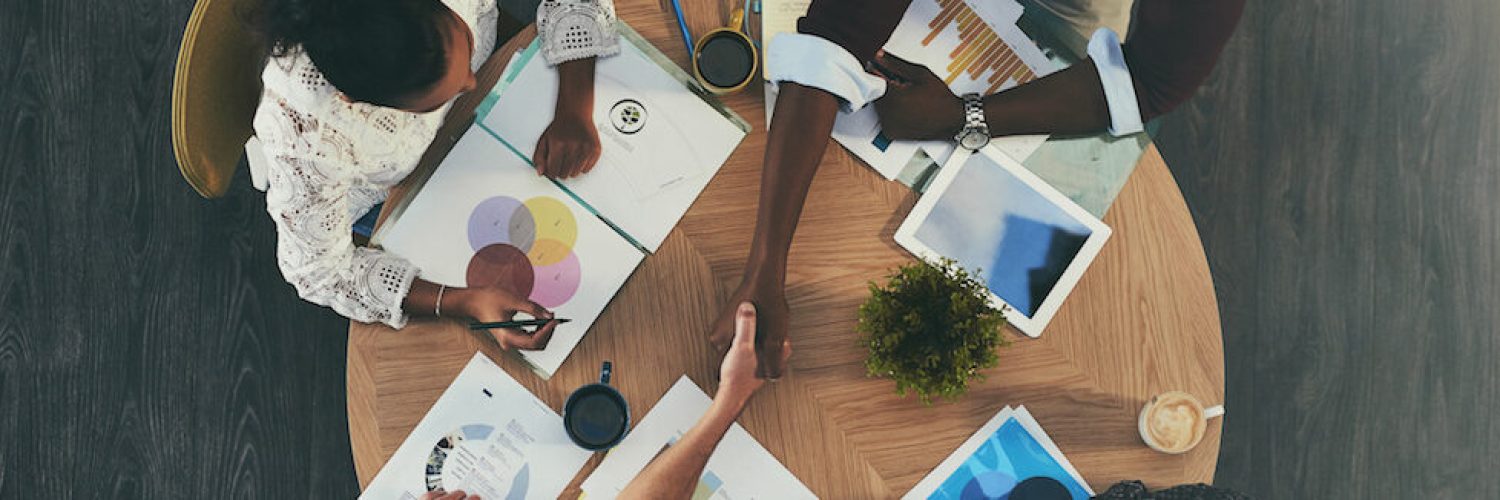 High angle shot of businesspeople shaking hands during a meeting with colleagues.