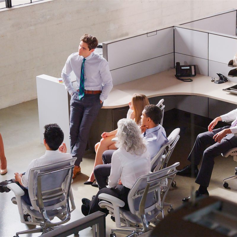 Businesswoman Standing At Whiteboard Giving Sales Presentation To Multi-Cultural Business Team
