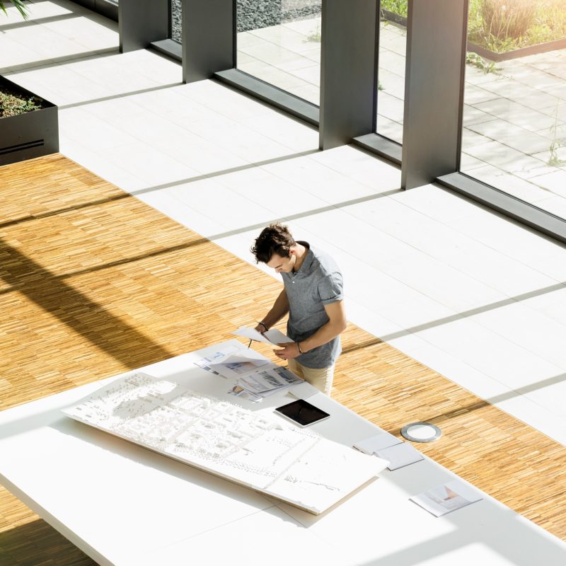 High angle view of young male architect working on an architectural model.